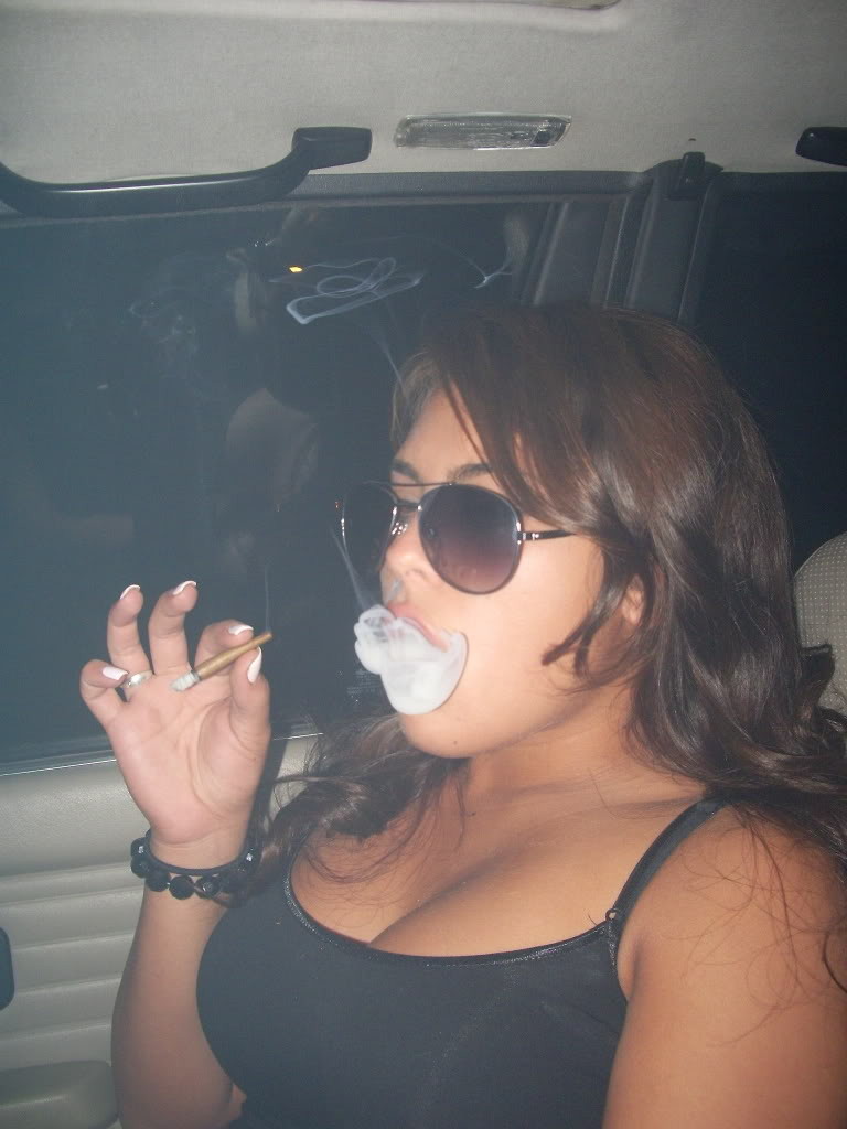 Stoner chick with big tits smokes a blunt photo