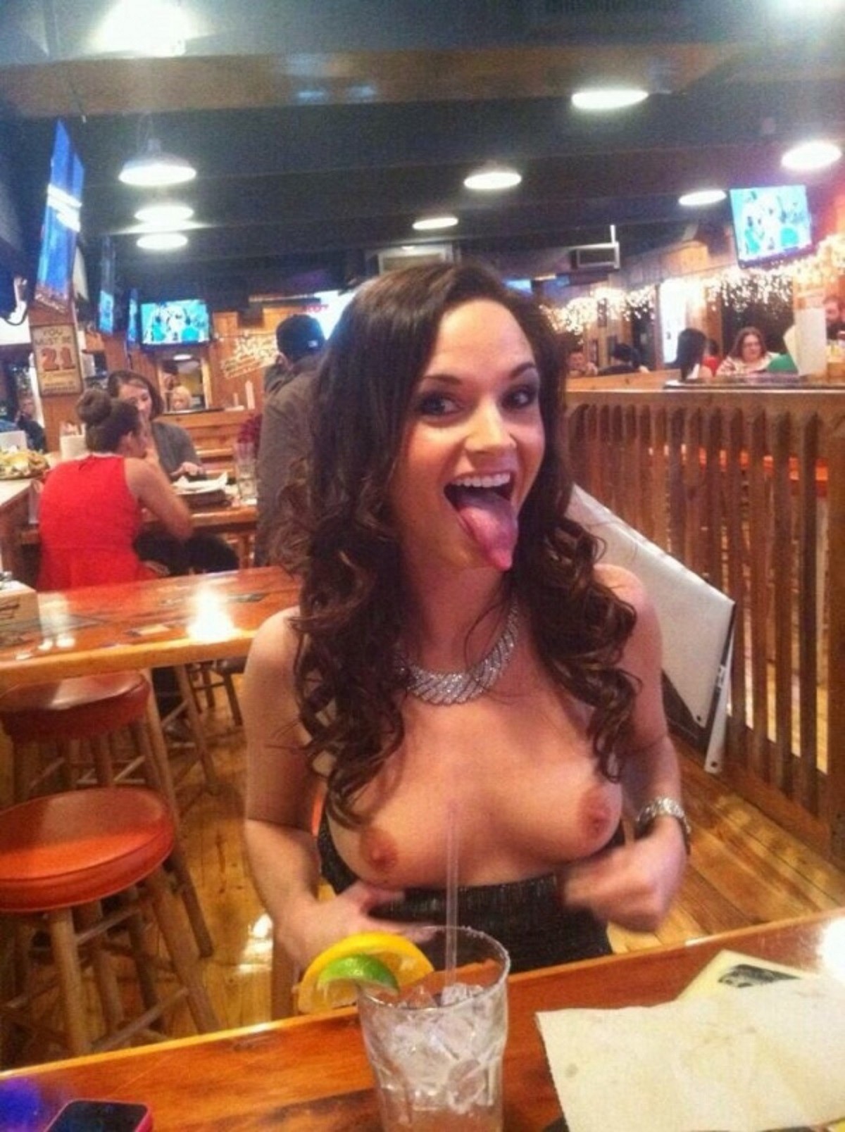 Girl flashes long tongue and boobs at the bar.